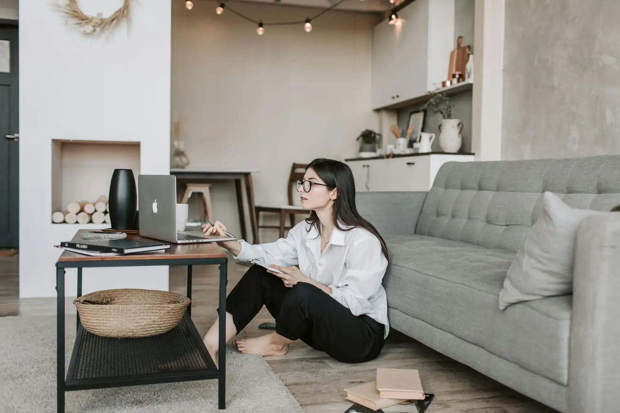 Woman sitting on the floor with a laptop and notepad. Fresh modern apartment interior.