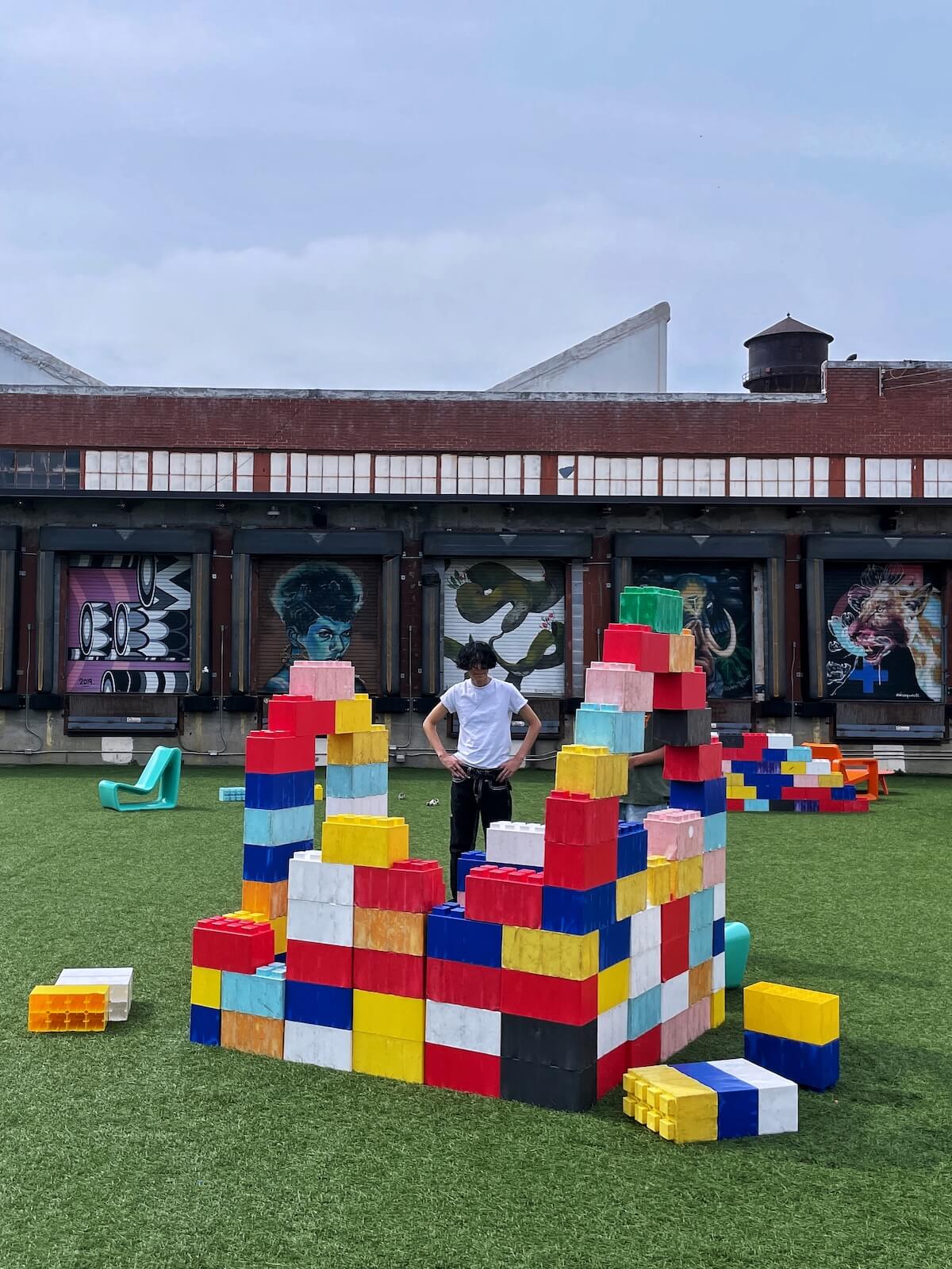 Man standing with hands on hips and looking at a structure made with giant legos at Camp North End in Charlotte.