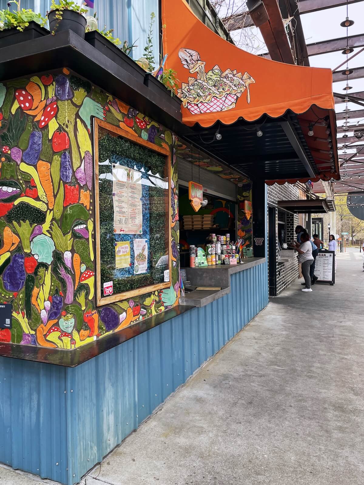Soul Miner's Garden outdoor food stall with orange awning and bright blue walls at Camp North End Charlotte