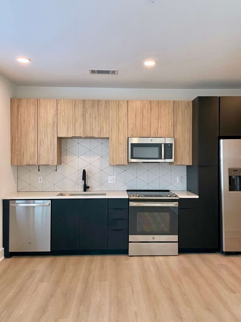 Contemporary kitchen with blonde wood uppers and dark lower cabinets in a studio apartment at Elan LoSo