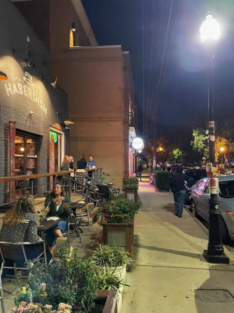 People eating at small tables outside of Haberdish in NoDa Charlotte at night
