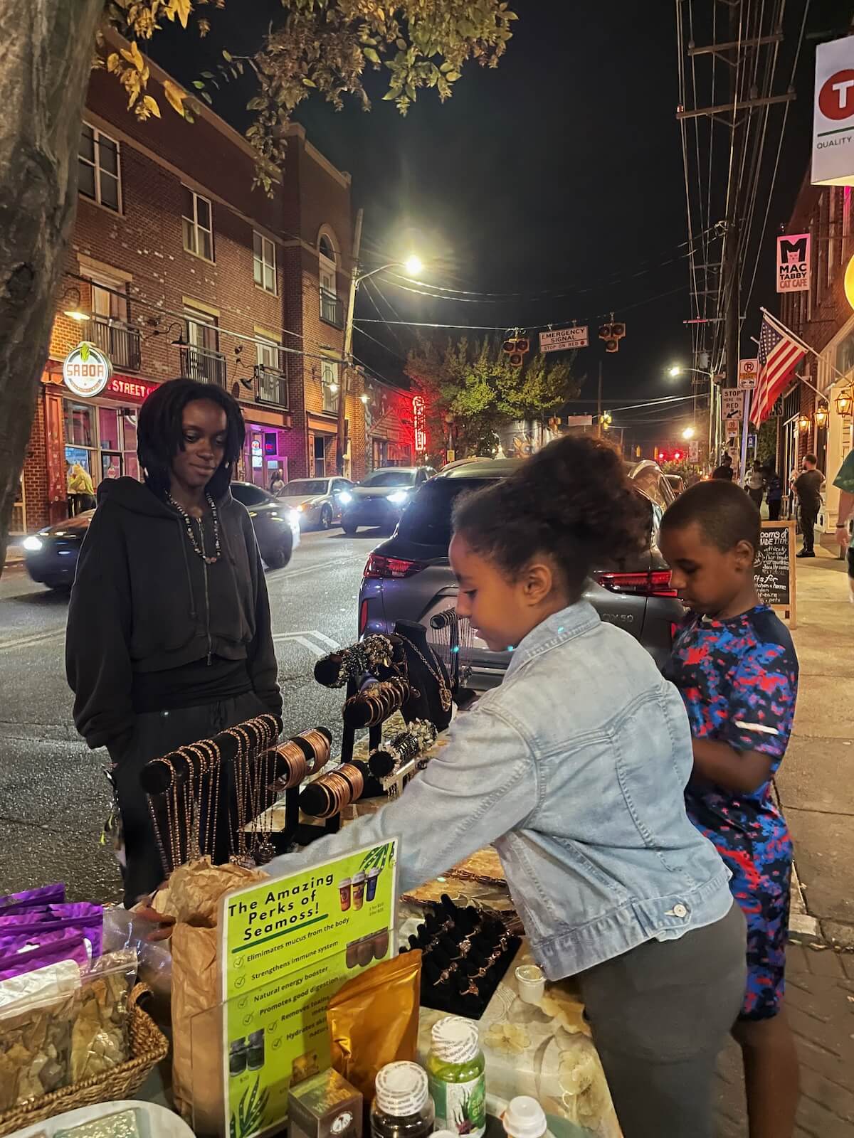 Two children look at handmade goods offered by a street vendor in NoDa Charlotte
