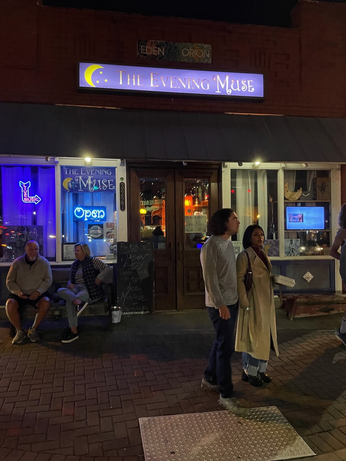 People standing outside of the Evening Muse live music venue in NoDa Charlotte at night