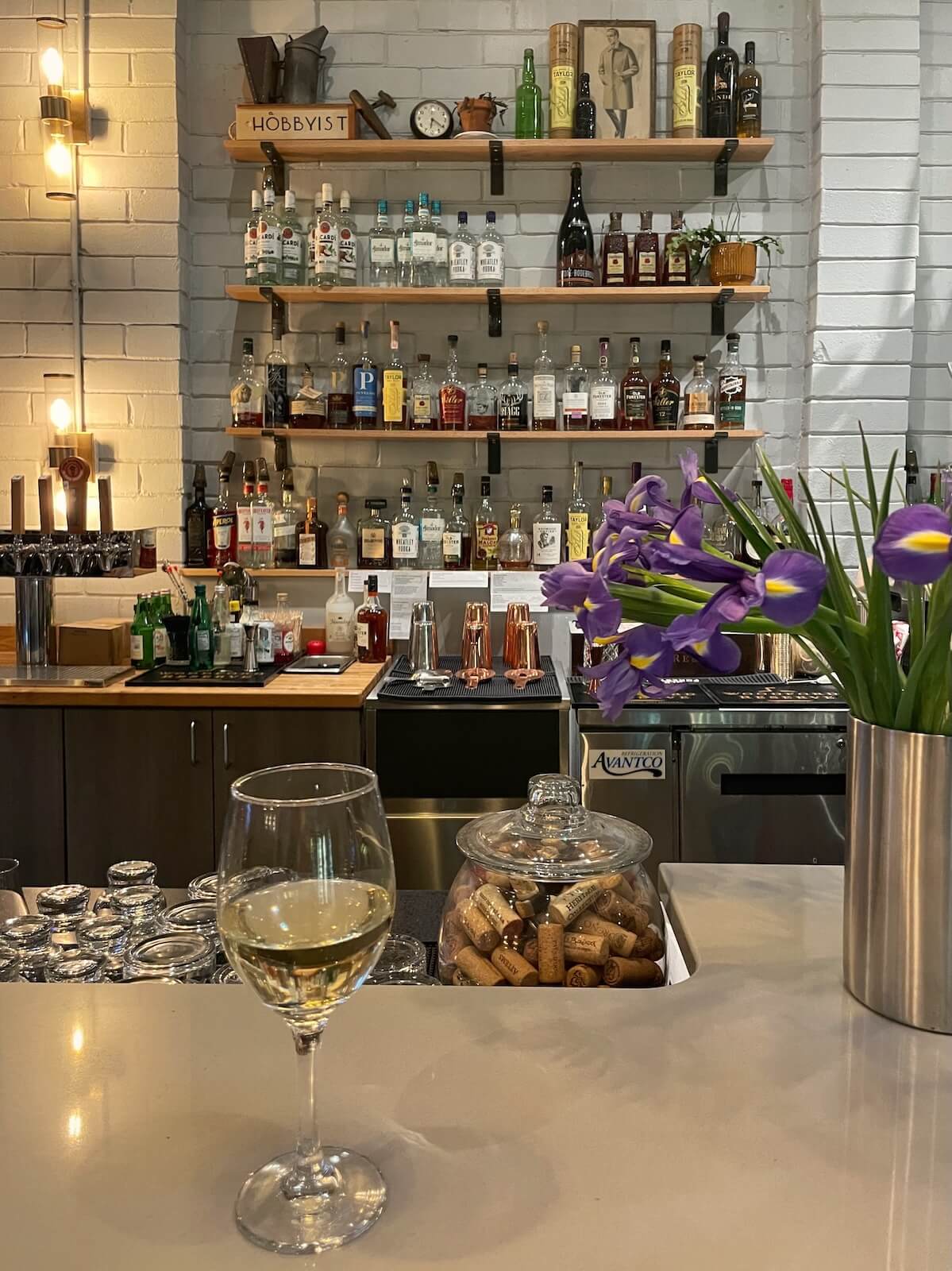 Glass of white wine on the bar with bar shelves in the background