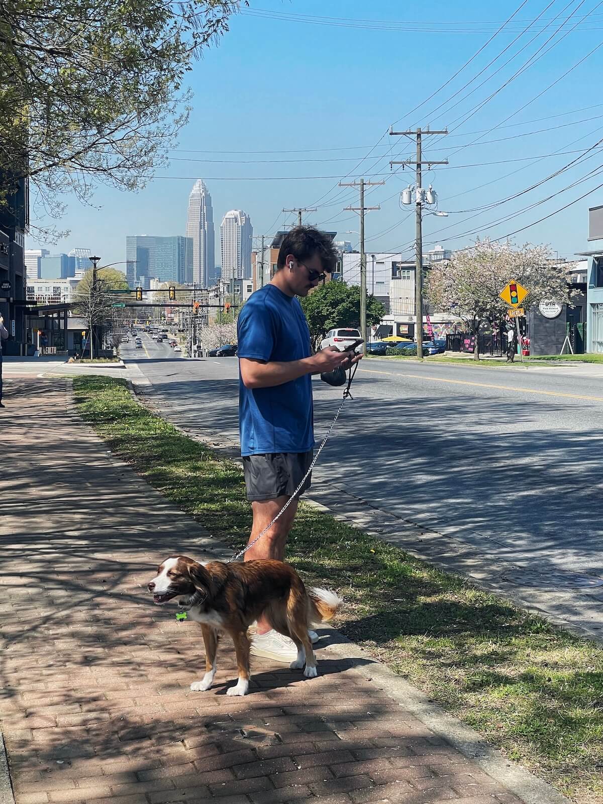 Man standing on sidewalk with view of Uptown Charlotte in the background