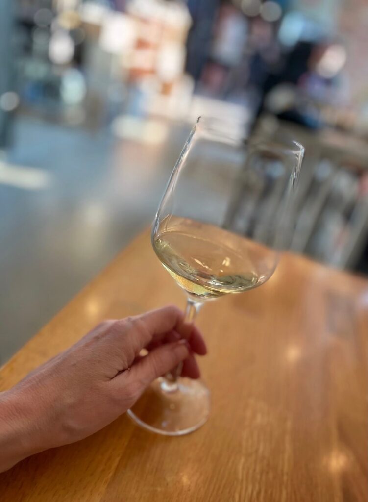Woman's hand with glass of wine and a busy restaurant in the background
