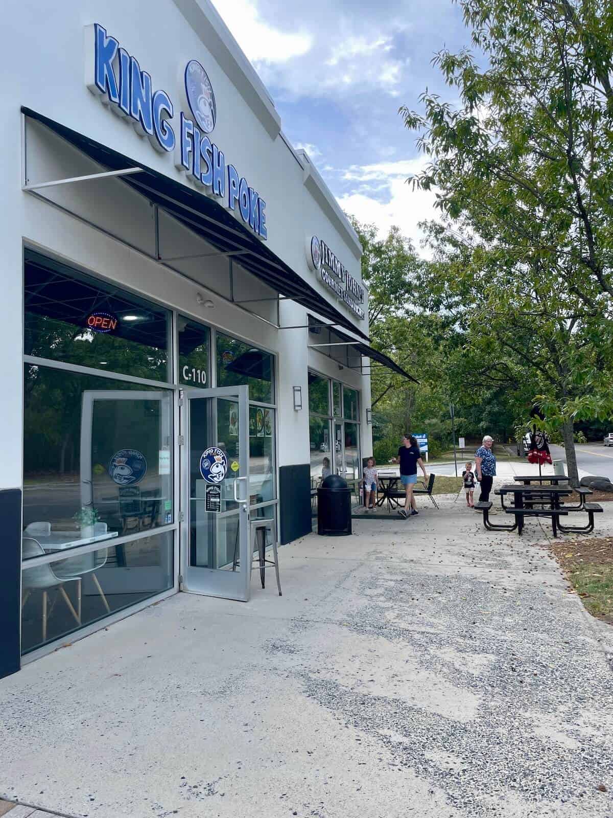 Exterior view of King Fish House fast casual restaurant with outdoor seating and trees in University City Charlotte