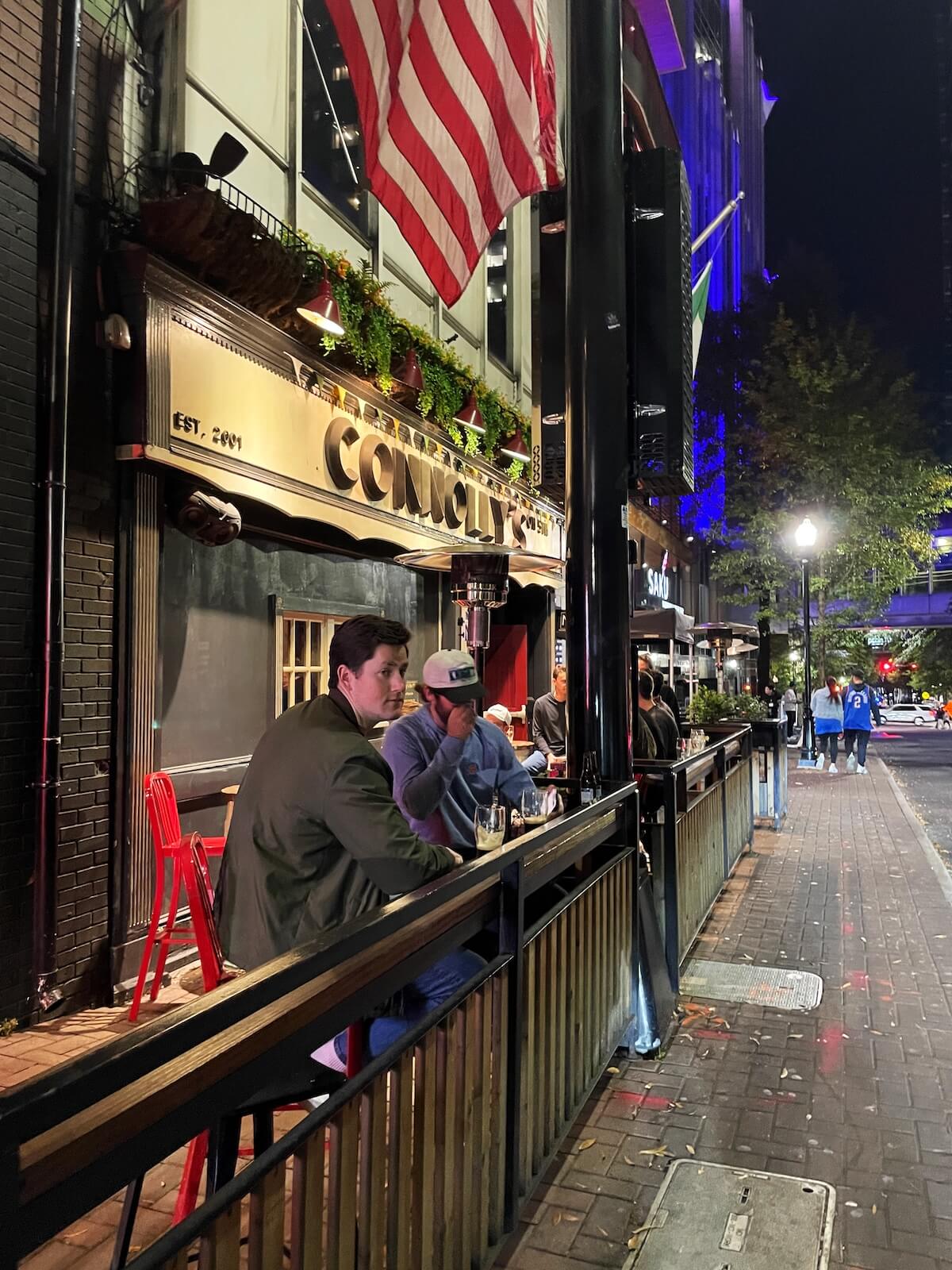 people sitting outside of an Irish pub in Uptown Charlotte at night

