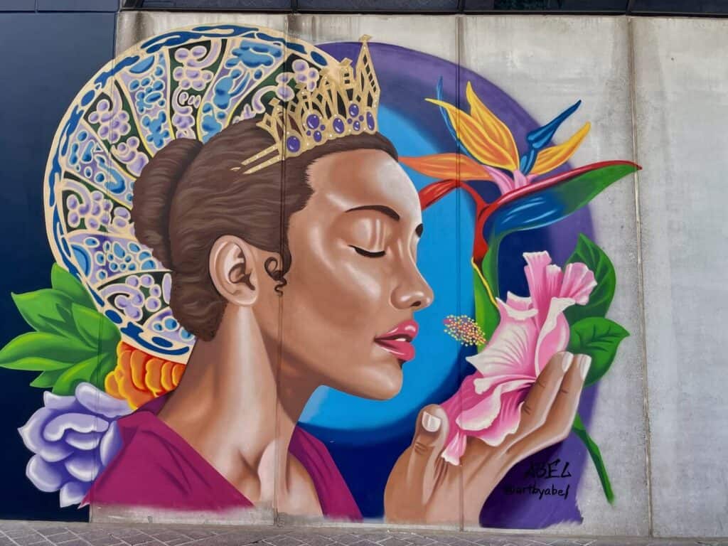 Charlotte's Queen, painted by Abel Jackson is a colorful mural of a woman wearing a crown and holding a pink flower in Uptown Charlotte