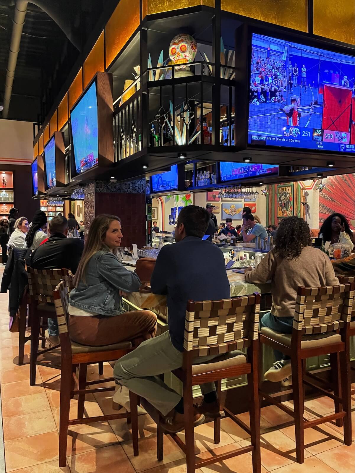 People sitting at a bar with TVs at a restaurant in Uptown Charlotte