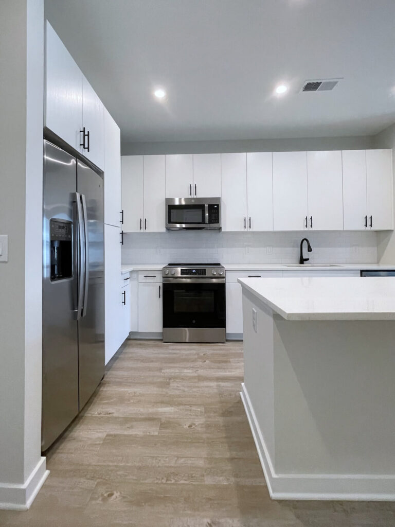 Modern kitchen with stainless steel refrigerator, oven, microwave, and white cabinetry in a 1 bedroom apartment at MAA Plaza Midwood in Charlotte.