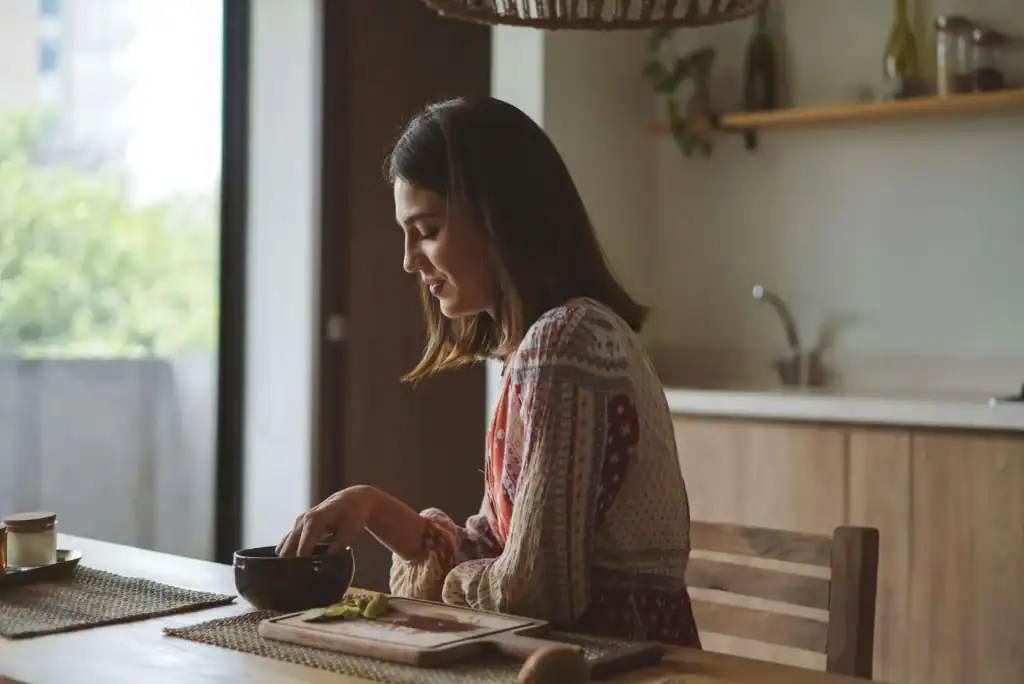 Woman enjoying breakfast in a cozy kitchen with natural light.
