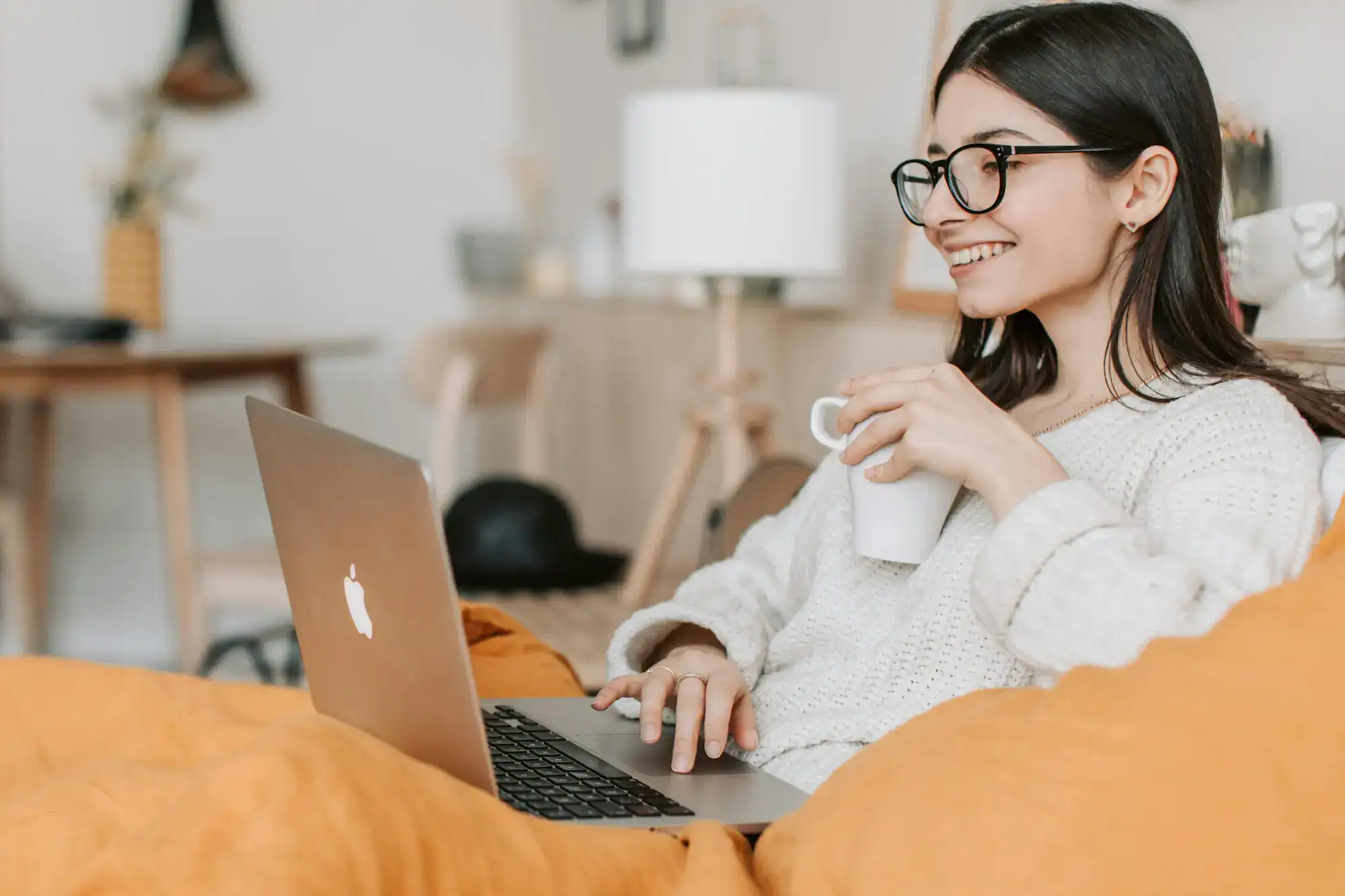Woman enjoying coffee while reading on her laptop.