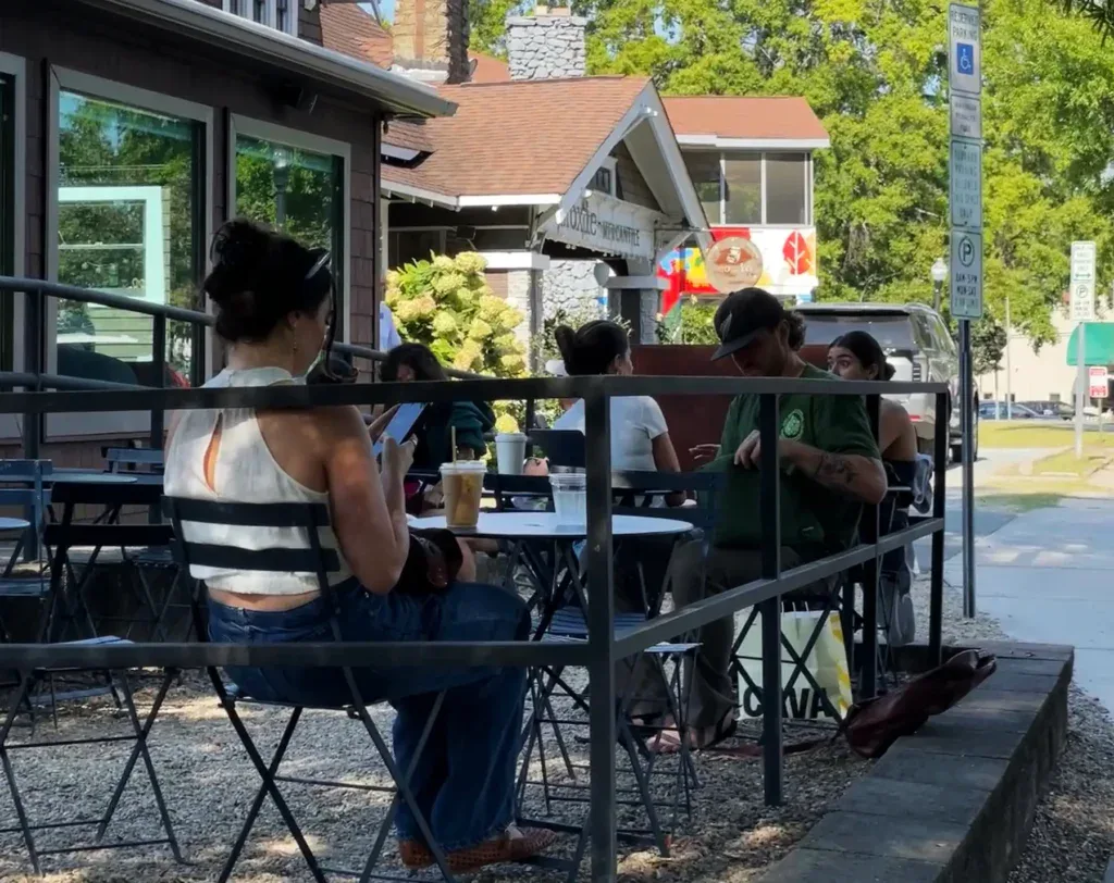 People sitting at tables at a sidewalk cafe in Plaza Midwood Charlotte